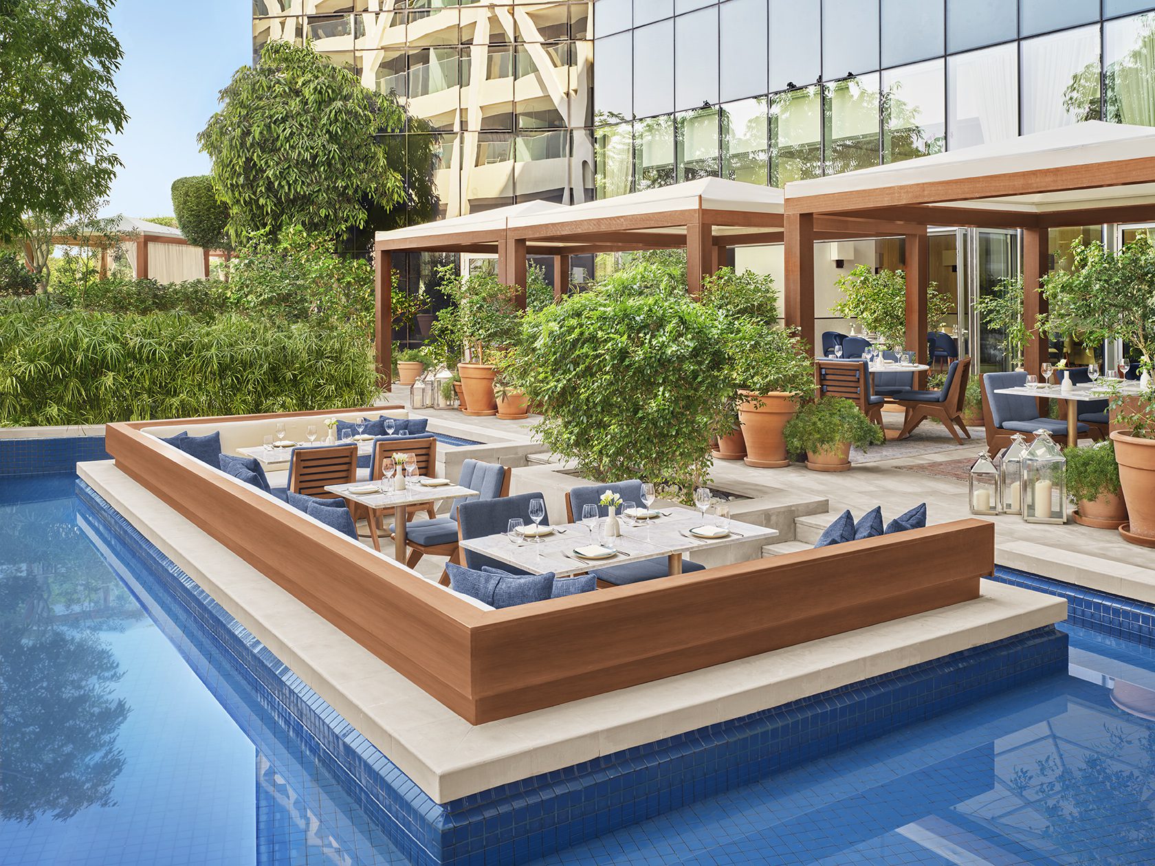 An outdoor dining area on a platform in the middle of a pool.